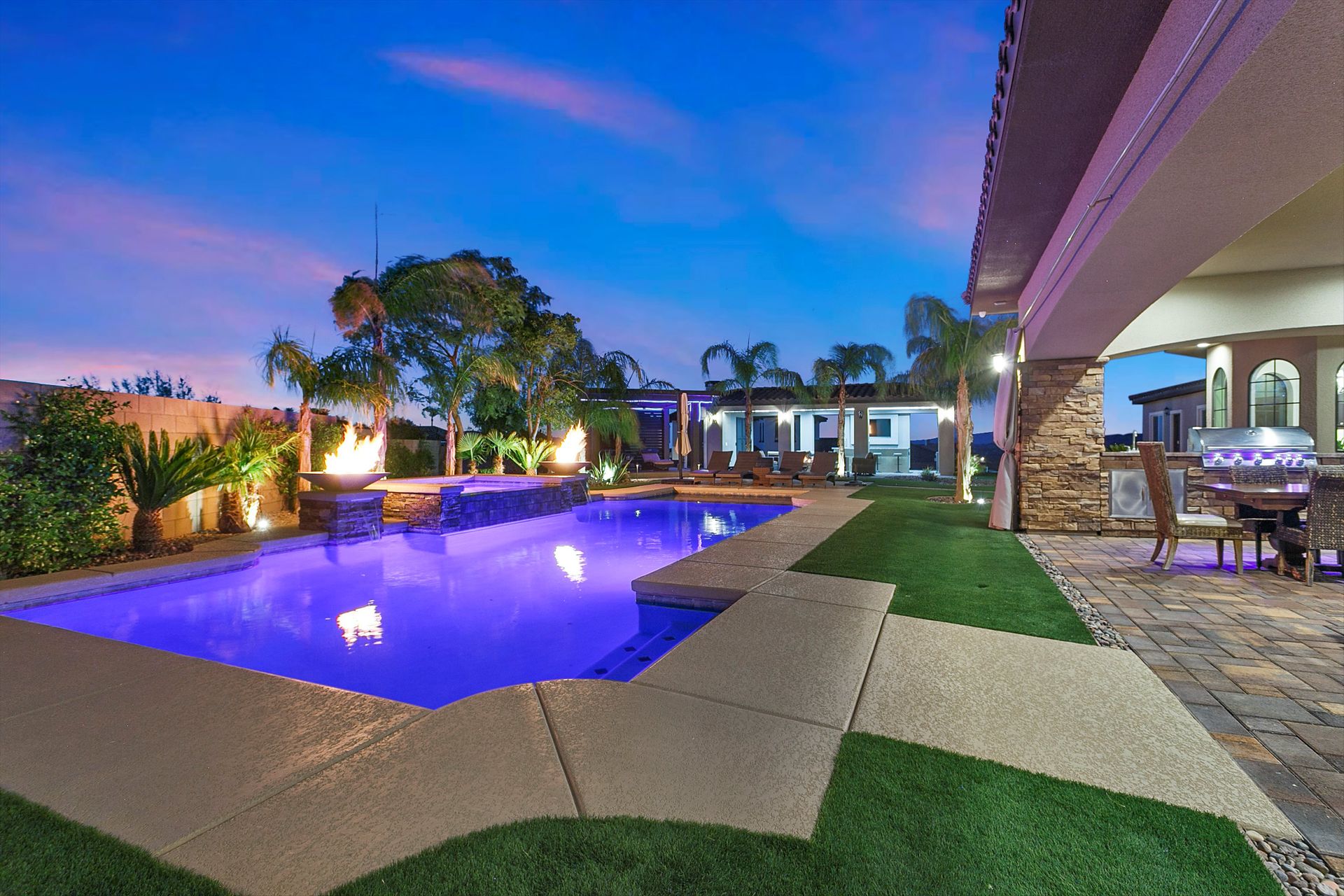 Luxury backyard pool with LED lighting, fire features, and custom patio design by H And H Pools LLC in Las Vegas.